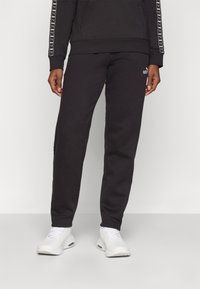 Schwarzes Sweatshirt- und Hosen-Set mit weichem Textil, elastischem Bund und weißen Logodetails. Entwickelt für Komfort und legere Kleidung.