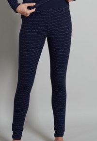 Leggings blu navy realizzati in tessuto morbido ed elastico, caratterizzati da un motivo a linee ondulate bianche, con una vita elasticizzata e una silhouette aderente.