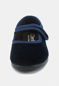 Scarpa vellutata blu navy con punta arrotondata, dotata di una fascia in tessuto sulla parte anteriore e una soletta morbida e testurizzata per il massimo comfort.