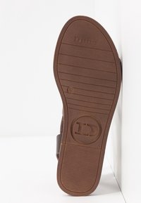 Semelle de sandale marron avec un logo circulaire, taille 37, et des rainures horizontales, présentée sur fond blanc.