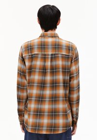 Geruite shirt in oranje, zwart en wit. Heeft lange mouwen, knopenmanchetten en een rugpand met plooien. Textuurstof.