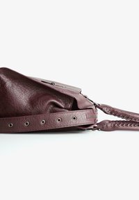 Burgundy nahkalaukku, jossa on laatikkomainen pinta, vetoketjullinen tasku ja kudotut hihnadetailit. Varustettu hopeisilla yksityiskohdilla ja napsautuslukolla.