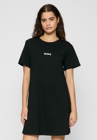 Fekete pamut t-shirt ruha rövid ujjakkal és kerek nyakkivágással. Fehér "Girl Gang" felirat található a mellkasán. Egyszerű, laza fazonú.
