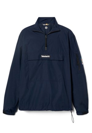 Tiffanysin sinimust pullover jakk, mis on valmistatud kergest kangast, pool-zip ees, suure rinna taskuga ja elastsete mansettidega, millel on nööriga alumine serv.