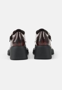 Glossy burgundy patent leather shoes with a chunky black heel, features a silver buckle accent and sleek rounded shape.