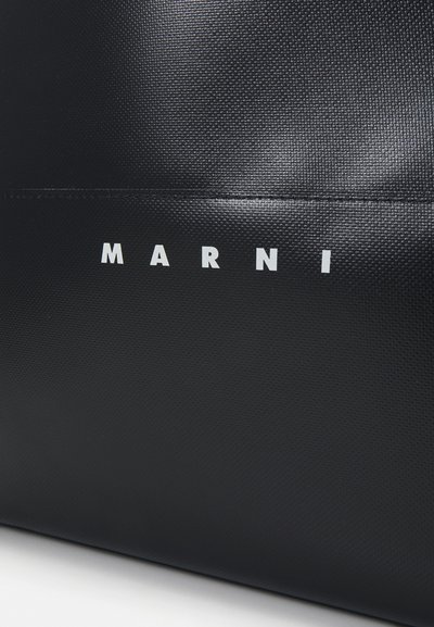 Borsa a tracolla nera con texture, caratterizzata da un logo bianco prominente "MARNI" sulla parte frontale, progettata con un'estetica minimalista.