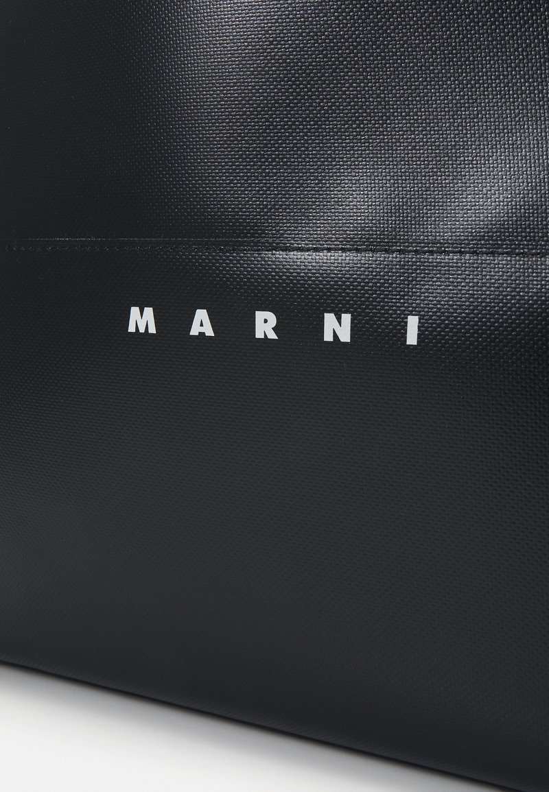 Sac fourre-tout noir texturé avec un logo blanc saillant "MARNI" à l'avant, conçu avec une esthétique minimaliste.