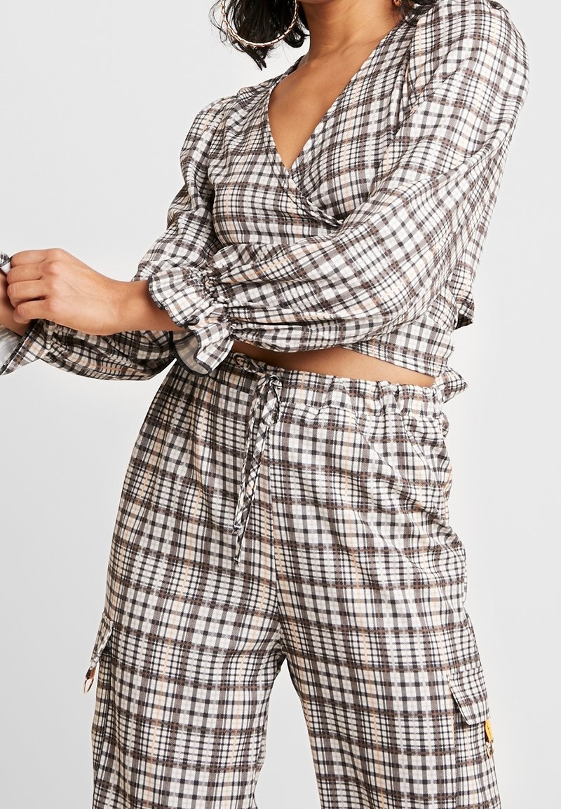 Crop-Top- und Hosen-Set im karierten Muster. Das Top hat lange Puffärmel und einen tiefen V-Ausschnitt; die Hose hat einen elastischen Bund und Taschen.