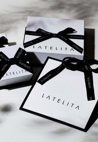 Three gift boxes in varying sizes feature a white background with black accents. The brand name "LATELITA" is printed in bold black font on each box.