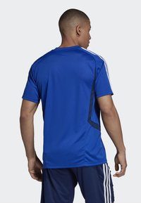 Blaues Sporttrikot aus glattem, atmungsaktivem Stoff. Verfügt über kontrastierende marineblaue Seitenpanels und weiße Streifen an den Schultern. Kurzärmliges Design.