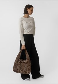 Sac hobo en imprimé léopard brun et noir, fabriqué en tissu avec une texture douce. Il dispose d'une seule anse et d'une forme décontractée et en flanelle.
