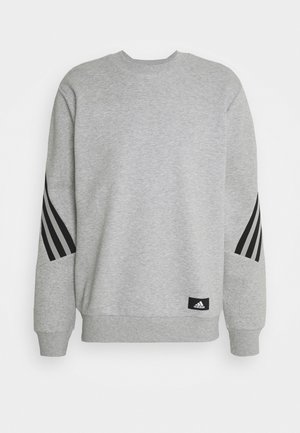 Sweatshirt Adidas gris clair avec des rayures diagonales noires sur les manches et un petit patch avec le logo Adidas près de l'ourlet, col rond et poignets côtelés.