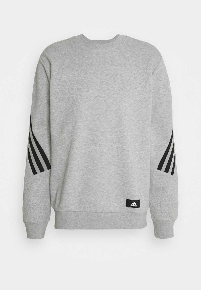 Sweatshirt Adidas gris clair avec des rayures diagonales noires sur les manches et un petit patch avec le logo Adidas près de l'ourlet, col rond et poignets côtelés.