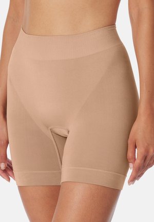 Gros plan sur une personne portant un short gainant nude sans couture à taille haute, d'une longueur mi-cuisse et au tissu lisse.