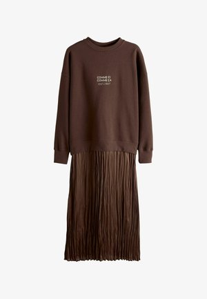 Brown sweatshirt with printed text at the chest, paired with a pleated brown skirt. The fabric is soft with a textured finish.