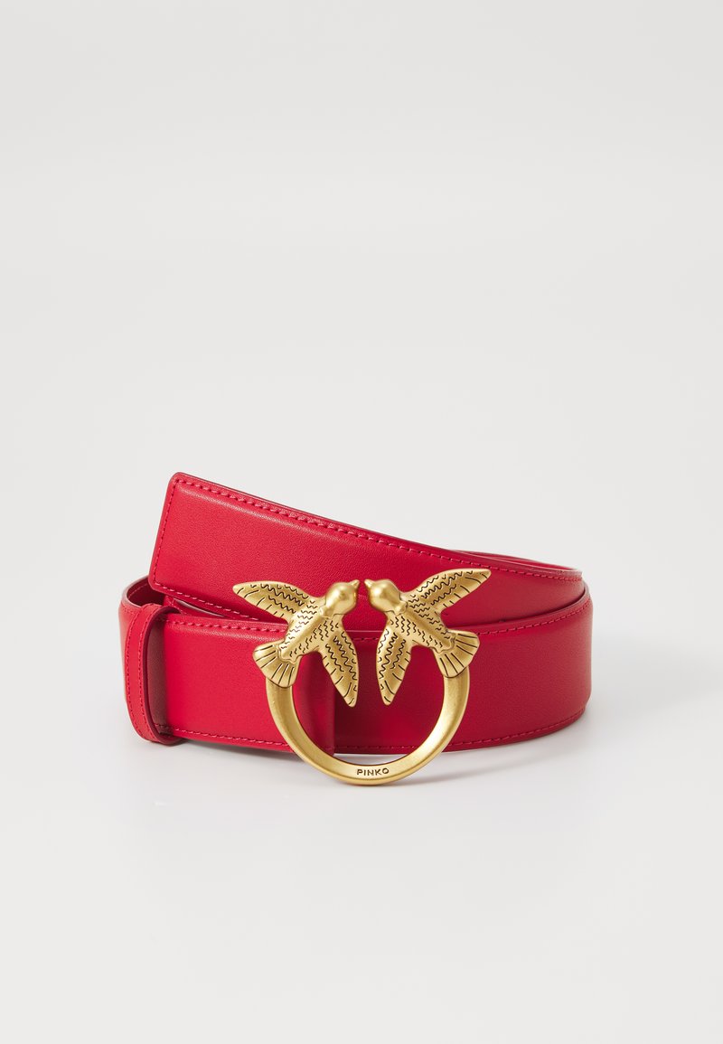 Ceinture en cuir rouge avec une boucle circulaire dorée ornée de deux motifs d'oiseaux. Texture lisse et design élégant.
