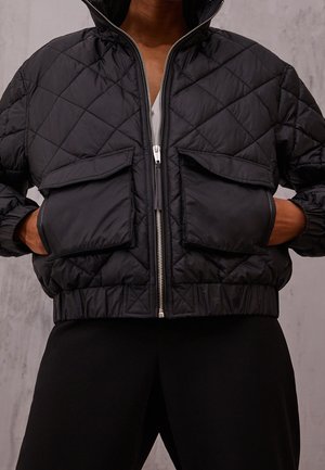 Zwarte gewatteerde bomberjack met een hoge kraag, voorzien van een ritssluiting aan de voorkant en twee opgestikte zakken, gemaakt van glanzend, gestructureerd materiaal.