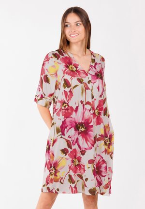 Leren jurk van lichte stof met een V-hals, voorzien van grote roze en gele bloemen op een bleke achtergrond, korte mouwen en een losse pasvorm.