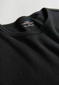 Black thermal shirt with a round neckline, ribbed texture, and tag displaying "NEXT THERMALGEN M" made in Bangladesh.