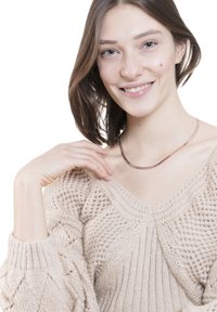 Halsketting met een gladde, glanzende metalen afwerking, gelaagd ontwerp in een eenvoudige, gebogen vorm. Model draagt een beige gebreide trui met een V-hals.