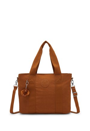 Brun shopper med to greb, justerbar skulderrem, rundt mærke med logo og en lille abe-nøglering fastgjort foran.
