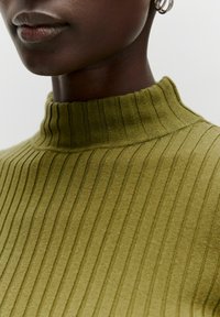Olivgrüner gerippter Rollkragenpullover mit hohem Kragen, weicher Textur und feinen vertikalen Streifen, der das enganliegende Design betont.