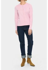 Rosa långärmad cardigan med rund ringning och knäppning fram. Tillsammans med mörkblå jeans och tanfärgade ankelskor med spetsiga tår.