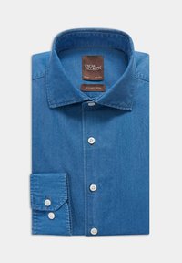 Chemise en denim slim-fit bleu clair, présentant un devant à boutons, un col pointu et des manches longues avec des poignets à boutons. Étiquette de marque marron à l'intérieur.