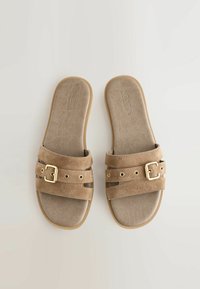 Sandales à talon en daim marron avec deux lanières horizontales, ornées de boucles dorées et de trous décoratifs, présentant un coussin de pied texturé et doux.