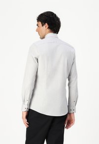 Light gray checkered shirt with long sleeves, buttoned cuffs, and a classic collar, featuring a subtle texture and a tailored fit.