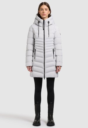Light gray puffer coat with horizontal stitched pattern, high collar, adjustable drawstrings, front zipper, and side pockets, worn with black leggings and boots.