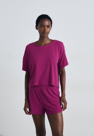 Fuchsia paarse geribbelde gebreide top met korte mouwen en cropped zoom, gecombineerd met bijpassende shorts met een elastische tailleband en knoopdetail.