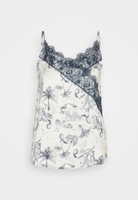 Camisole blanche avec imprimé tropical noir et bordure en dentelle noire au niveau du décolleté et des bretelles, vue de face sur fond uni.