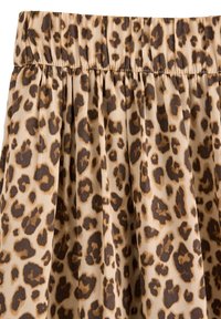 Leopardmönstrad kjol med en beige bakgrund och mörkbruna fläckar, samlad midja och mjukt, texturerat tyg.