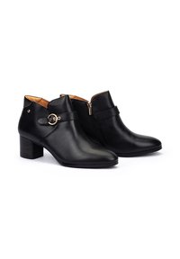 Botas de tobillo de cuero negro con punta afilada, tacón cuadrado, cremallera lateral y correa decorativa con herrajes en tono dorado. Textura suave.