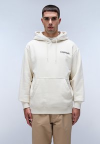 Felpa crema con tasca frontale, cappuccio regolabile e dettagli con logo. Tessuto morbido, vestibilità rilassata, maniche lunghe. Abbinata a pantaloni beige.