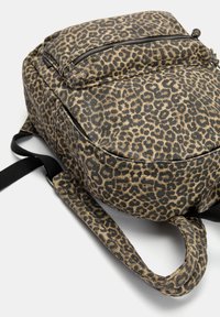 Rucsac din material cu imprimeu leopard, de formă rotundă, cu un buzunar superior cu fermoar și bretele negre, având o textură netedă și un material rezistent.