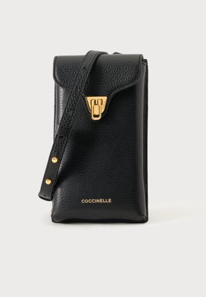 Sac bandoulière en cuir noir texturé avec fermoir doré et bandoulière réglable, signé « Coccinelle » en lettres dorées.