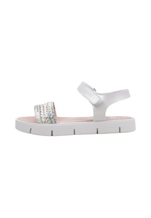Sandalia blanca con puntera abierta, suela gruesa, correa al tobillo con velcro y correa trenzada multicolor en la parte delantera.