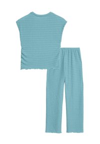 Lichtblauwe twee-delige set, met een korte mouwen top en een broek. Getextureerde stof met een ontspannen pasvorm en gegolfde randen.