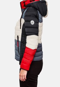Prošívaná bunda s kombinací černé, červené, modré a krémové barvy. Kapucňový design s elastickými stahovacími šňůrkami a nášivkou s logem na rukávu.