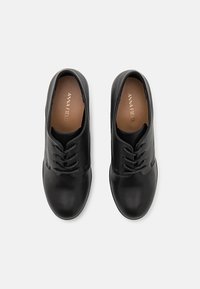 Chaussures en cuir noir à finition lisse, bout arrondi et design à cinq œillets pour les lacets. Intérieur doté d'une semelle beige avec logo.