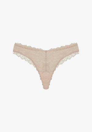 Lace thong in light beige, featuring floral patterns, scalloped edges, and a small decorative metal detail at the center front.