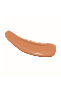 Campione di crema color pesco con una consistenza liscia e lucida, caratterizzato da una leggera forma a onda e una consistenza spessa, su uno sfondo bianco.