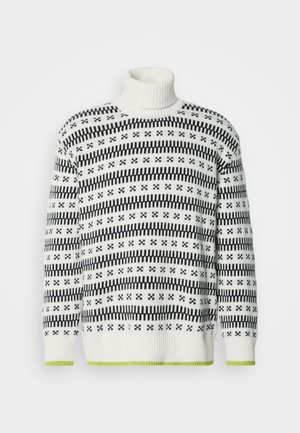 Balta megztinė su turtlenku, dekoruota juodais geometriniais raštais ir žaliu apvadu. Tekstūruota medžiaga, laisvas kirpimas ir gumbinė apykaklė.