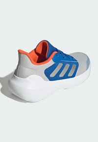 Baskets bleues et grises avec un dessus en mesh, intérieur orange et semelle intermédiaire blanche. Présente trois rayures métalliques argentées sur le côté.