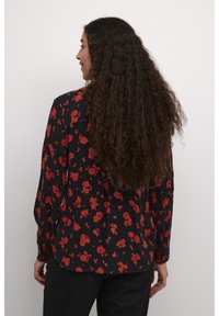 Lange mouwen blouse in zwarte stof met een rode bloemenpatroon, relaxed fit en een afgeronde zoom. Textuurstof met een zachte afwerking.