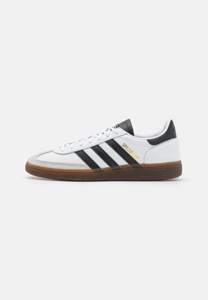 Hvid Adidas Spezial sneaker med sorte striber, gummisål og gul tekst "Spezial" på siden, vist fra ydersiden.
