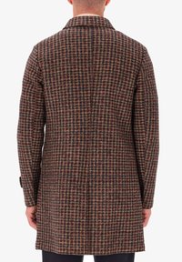 Cappotto in misto lana con motivo a quadri marrone e scuro, apertura posteriore singola, e polsini con bottone, dal taglio sartoriale e design a lunghezza media.