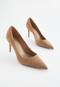 Décolleté in camoscio beige con punta appuntita e sottili tacchi a spillo. Texture liscia con design a taglio basso sul collo del piede.